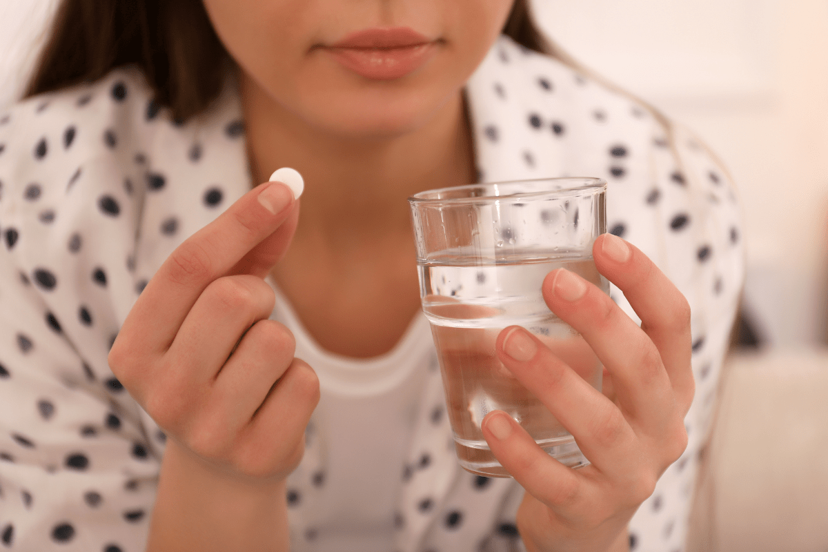 Girl holding a pill and glass of water